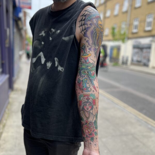 Full Old School Sleeve of Bright and Bold Western Traditional imagery featuring and Rose of No Man's Land, butterfly, cobwebs and grim reaper, dragon head and dagger. Filled in with Old School dots and stars filler. This tattoo was completed by Brighton Tattoo Artist, Antony Dickinson in East London UK