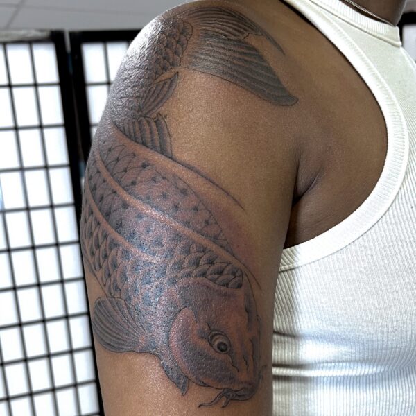A woman's arm featuring a fineline and feminine tattoo of a Japanese Koi Carp. This tattoo was drawn custom as a memorial for the clients Father. It was tattooed by Harriet at Nowhere Tattoo based in Sussex UK