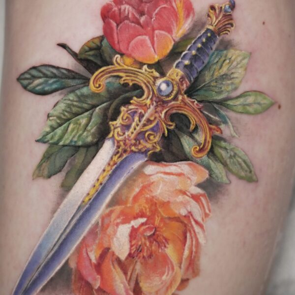 highly detailed, and colorful realism tattoo depicting a swords and flowers by Alex Rufio. Based at Nowhere Tattoo Shop in Brighton, Alex creates hyper realistic tattoos both in color, and black & white. He often creates tattoos of portraits, birds, snakes, and flowers.